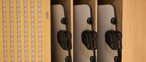 A wooden cabinet with a grid-patterned door and two compartments containing black objects.