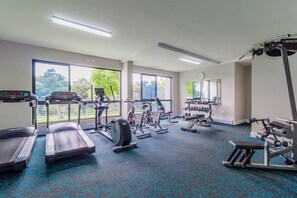 Un gimnasio con cintas de correr, bicicletas estáticas y máquinas de pesas.