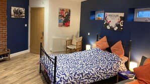 Een slaapkamer met een bed, een stoel, een radiator en posters aan de muur.