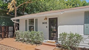 Une maison de plain-pied à l’extérieur blanc, avec le numéro « 905 » sur la porte et un petit porche avec des marches.