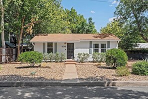 A single-story house with a front door, windows, and a small front yard with shrubs.