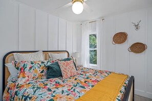 A bedroom with a bed, a window, and a ceiling fan.