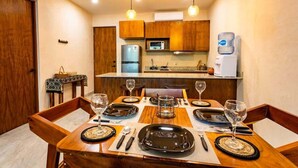 A dining area with a wooden table set for four, a microwave, and a refrigerator in the background. - MICAELA apartment, pool, AC next to the lagoon (Bárbara Guerrero Pérez)