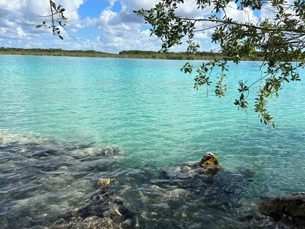 A clear turquoise sea with visible rocks and a distant shoreline.