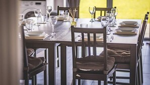 Een eettafel gedekt voor vier personen, met stoelen, glazen en bestek.