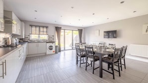 Een moderne keuken met een eethoek, een wasmachine en een aan de muur bevestigde televisie.