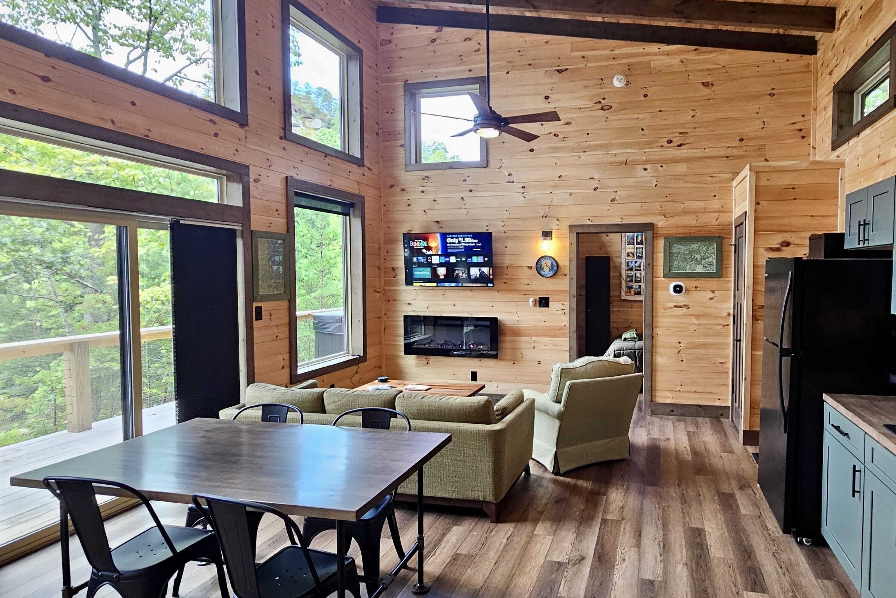 A spacious wooden cabin with a dining area, a living room with a fireplace, and a kitchen.