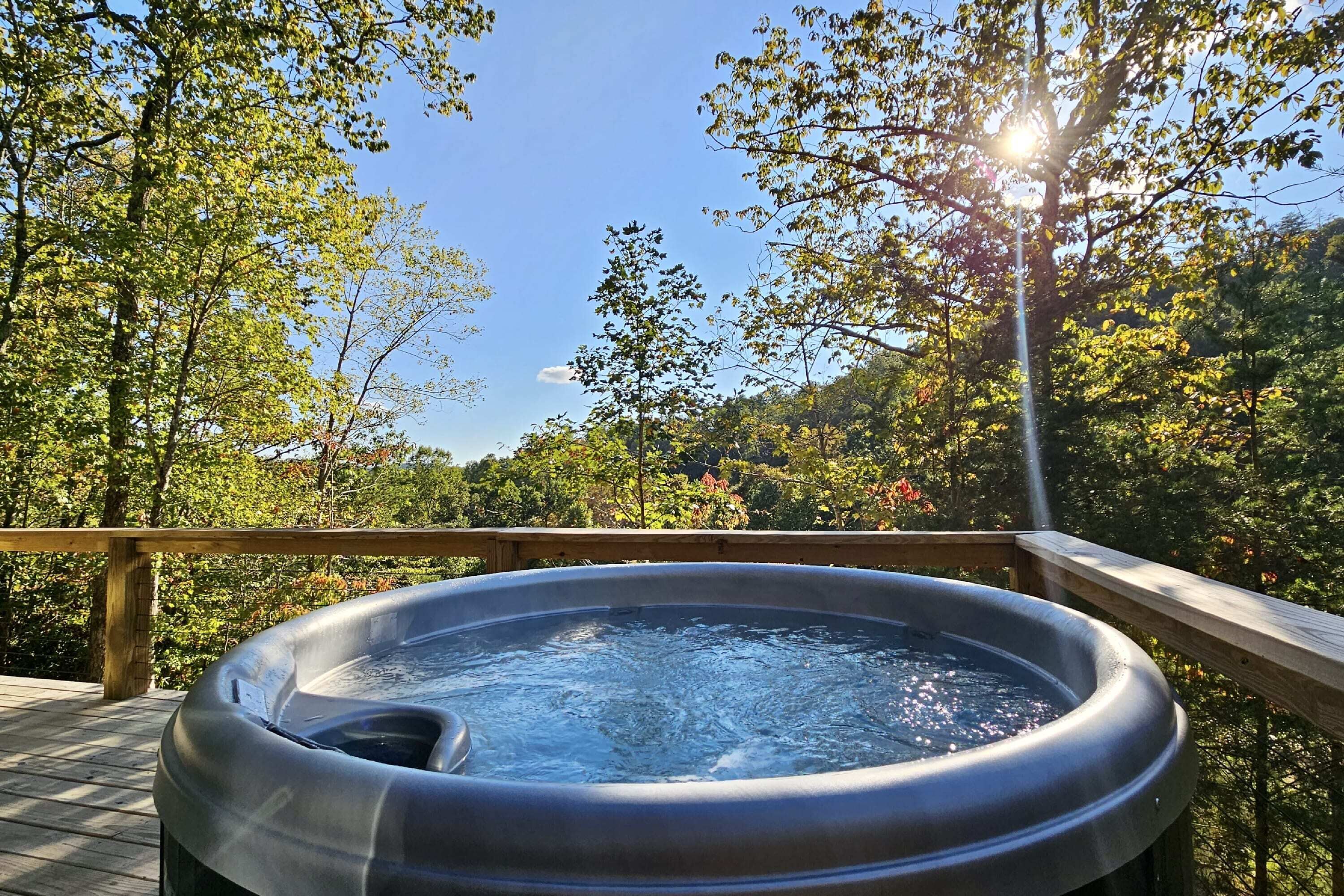 Un jacuzzi en una terraza de madera con vista al bosque.