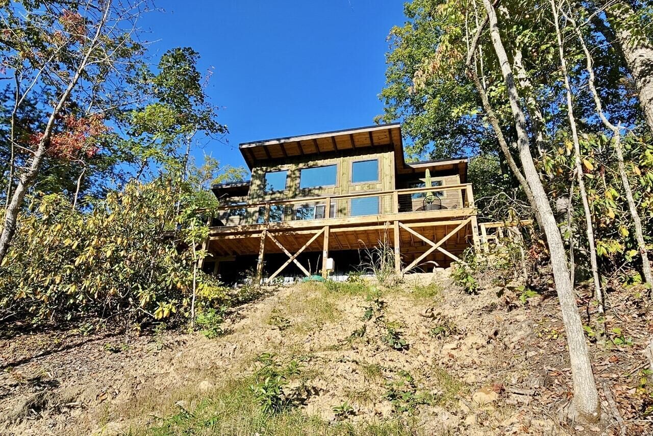 Une cabane en bois dotée d’une grande terrasse, entourée d’arbres.