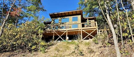 Une cabane en bois dotée d’une grande terrasse, entourée d’arbres.
