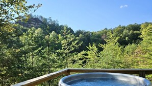 Un jacuzzi en una terraza de madera con vista al bosque.