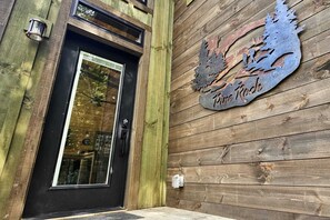 A wooden exterior wall with a metal sign reading "Pine Rock."