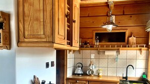A kitchen with wooden cabinets, a tiled backsplash, a kettle, a sink, and a hanging light fixture. - Mountain Cozy House in Tatras With Stunning View (Poronin)