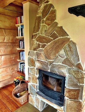 A stone fireplace with a bookshelf to the left.