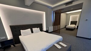 A modern hotel room with a large bed, a bedside table, a bench, and a mirror. - Gardan Hotel (Istanbul)