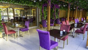 A restaurant with purple chairs and tables, glass partitions, and green plants. - Gardan Hotel (Istanbul)