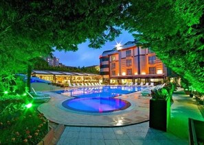 A hotel with a large outdoor swimming pool surrounded by lounge chairs and a well-lit building. - Gardan Hotel (Istanbul)
