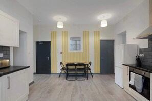 A modern kitchen with a dining table, chairs, and a black refrigerator.