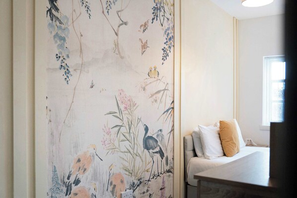 A room with a bed, pillows, and a wall with a nature-themed mural.