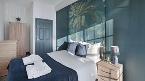 Une chambre à coucher avec un lit, une table de chevet, une commode et une porte.