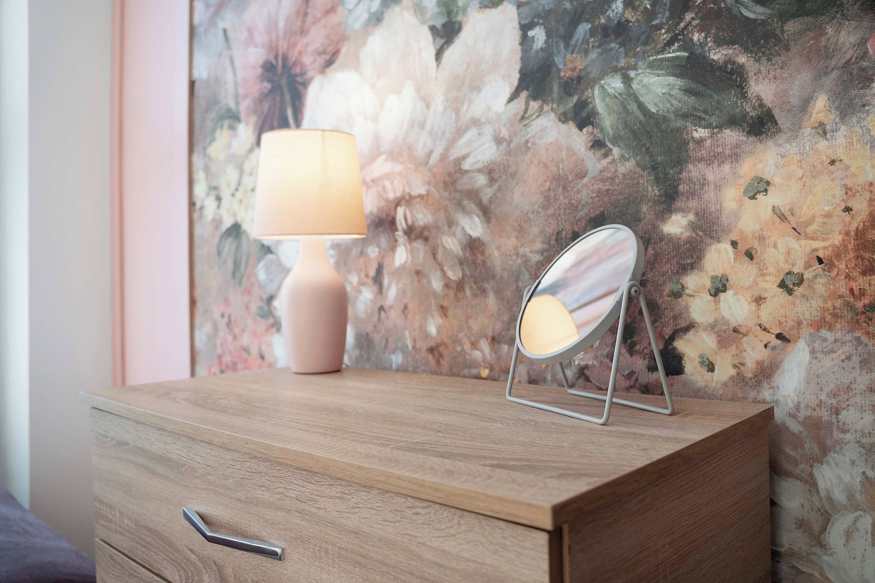 A wooden dresser with a drawer, a lamp, and a mirror.