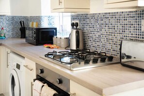 A kitchen with a gas stove, a microwave, and a toaster.