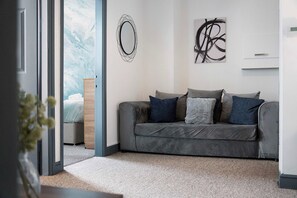 En moderne stue med en grå sofa, et træ sidebord og abstrakt kunst på væggen.