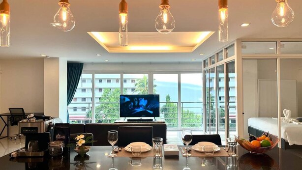 Habitación de hotel con comedor, televisión y balcón con vistas.