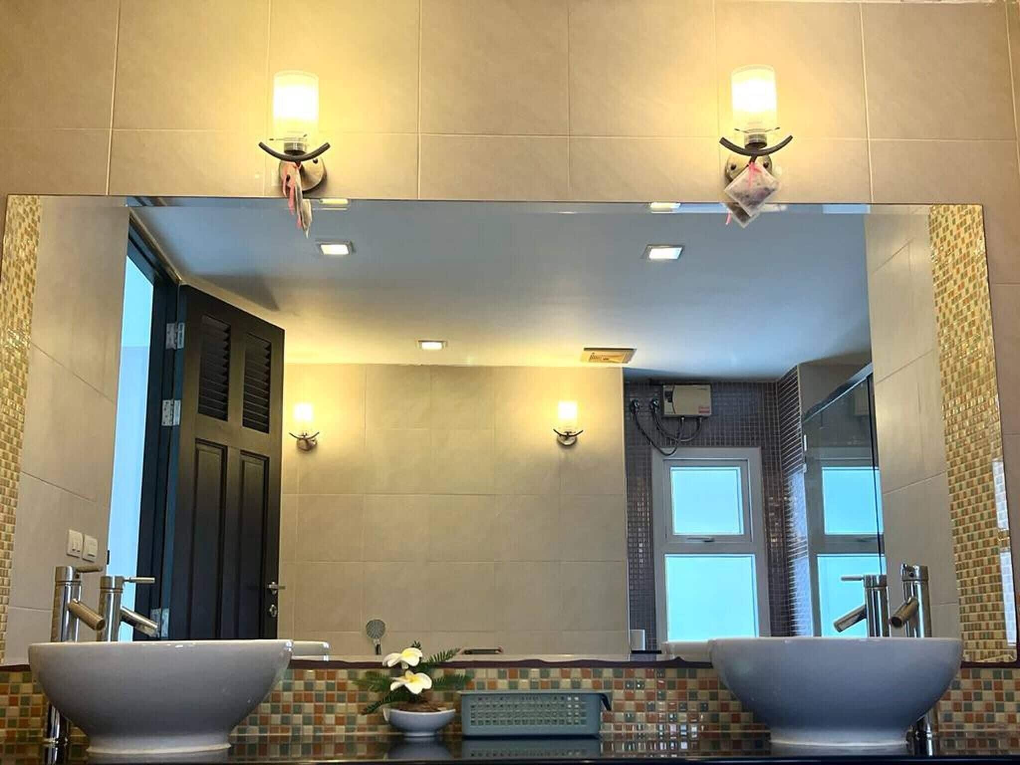 Un baño con dos lavamanos, un espejo e iluminación en la pared.