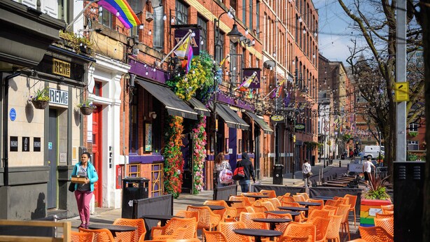 A street with outdoor seating and a building with a 'RENE' sign.
