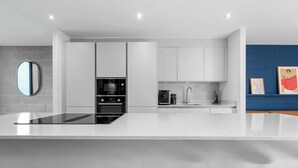 A modern kitchen with white cabinetry, a central island, and a blue accent wall.