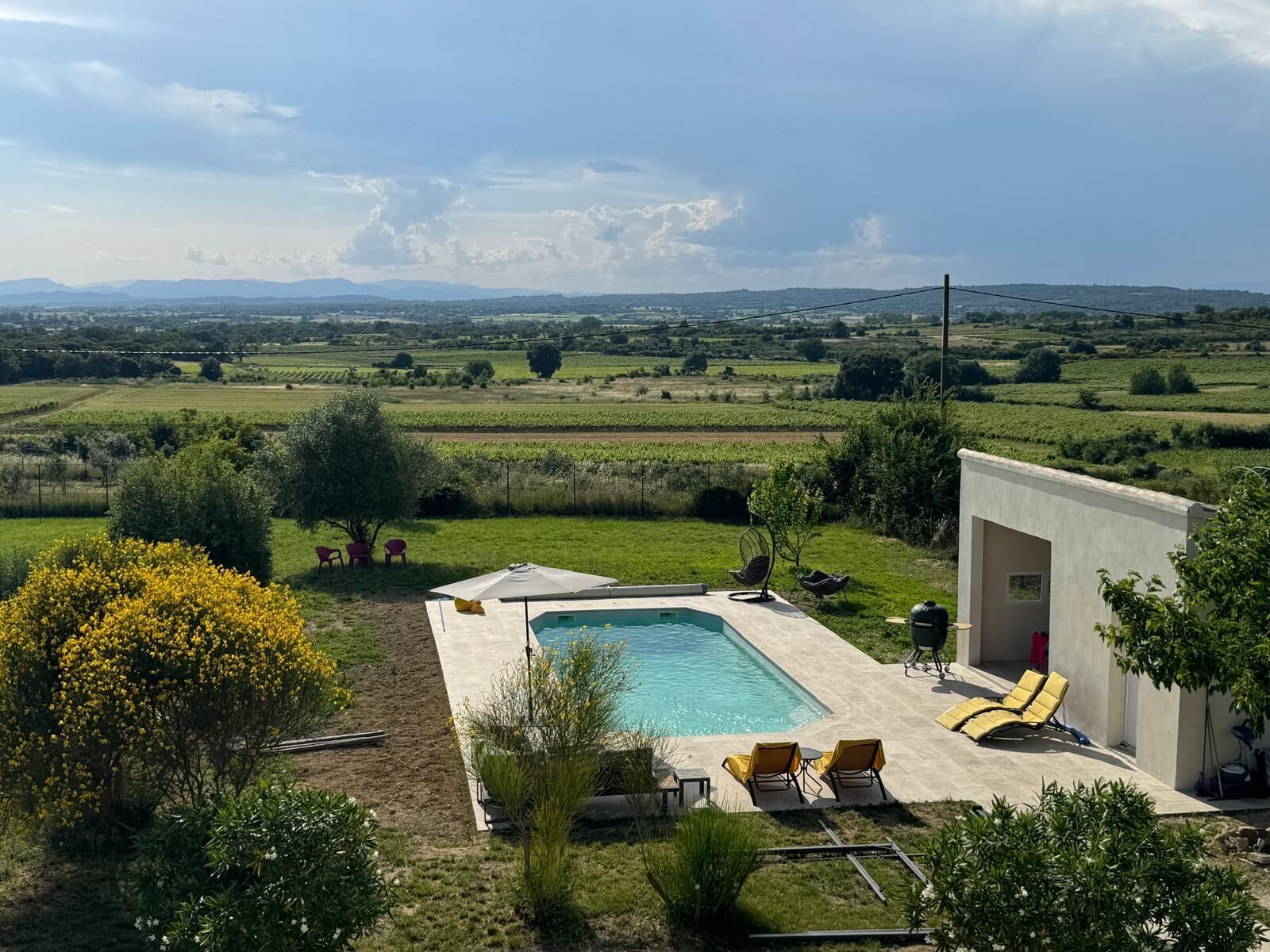 A pool area with a view of a rural landscape, including fields and distant mountains.