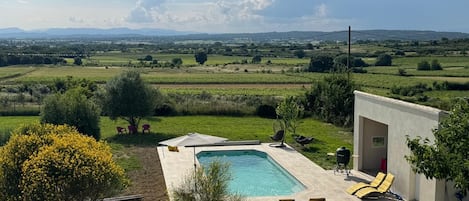 A pool area with a view of a rural landscape, including fields and distant mountains.