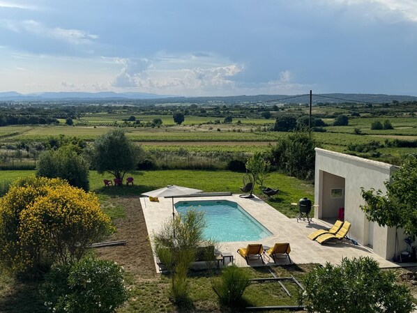 A pool area with a view of a rural landscape, including fields and distant mountains.