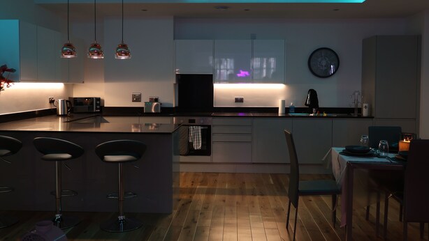 Une cuisine moderne dotée d’un îlot central, de tabourets de bar et de luminaires suspendus.
