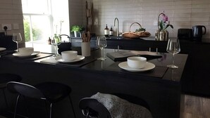 A modern kitchen with a central island, a dining area with chairs, and a view of the outdoors.