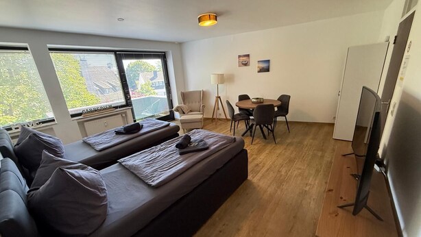 A modern living room with a sofa, a dining table, and a TV. - Moderne Ferienwohnungen und -zimmer in Kleve (Kleve)