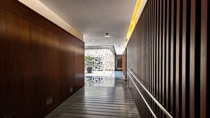A corridor with wooden paneling, a metal railing, and a geometric wall feature. - Cathedral Apartment Welcome Wheelchairs (Sevilla)