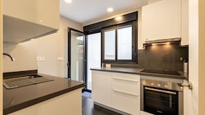 A modern kitchen with a built-in oven, a stovetop, and a window above the sink. - Cathedral Apartment Welcome Wheelchairs (Sevilla)
