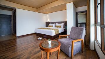 A hotel room with a bed, a chair, a small table, and a window.