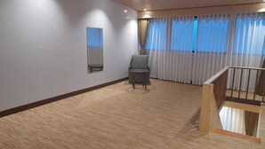 A spacious room with a wooden floor, a grey chair, a small table, and a wooden railing. - Sumitel Pelling (Gyalshing)