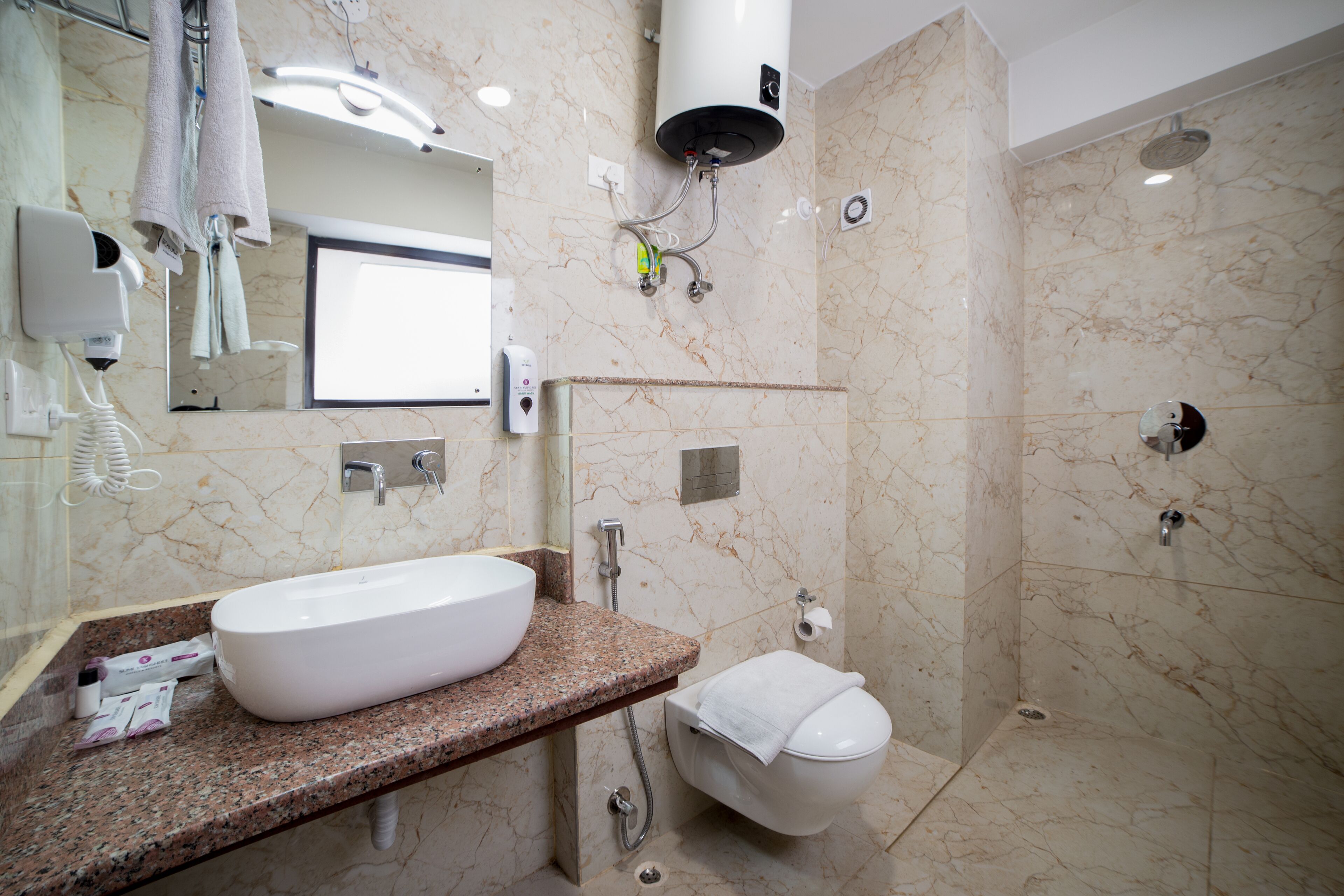 Un baño con pared de mármol, un lavamanos, un inodoro y una ducha.