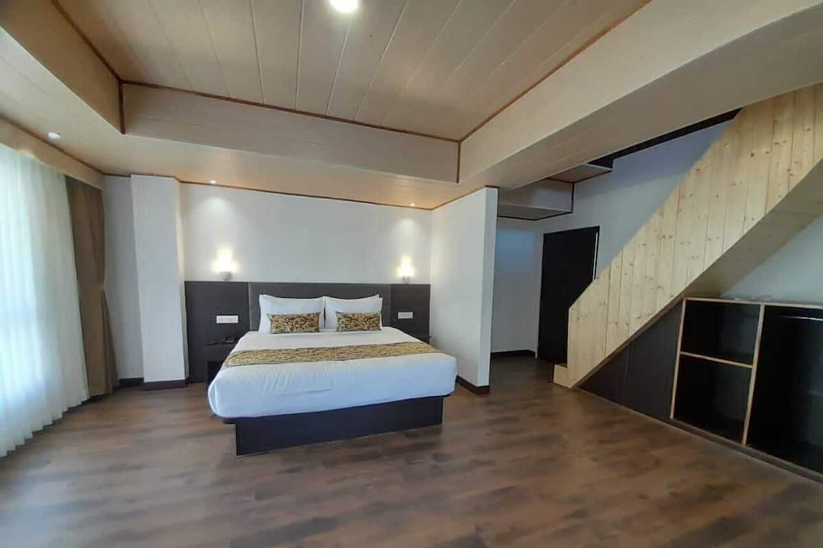 Um quarto moderno com uma cama grande, piso de madeira e uma escada.