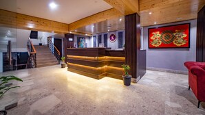 A reception area with a wooden reception desk, a staircase, and a red chair. - Sumitel Pelling (Gyalshing)