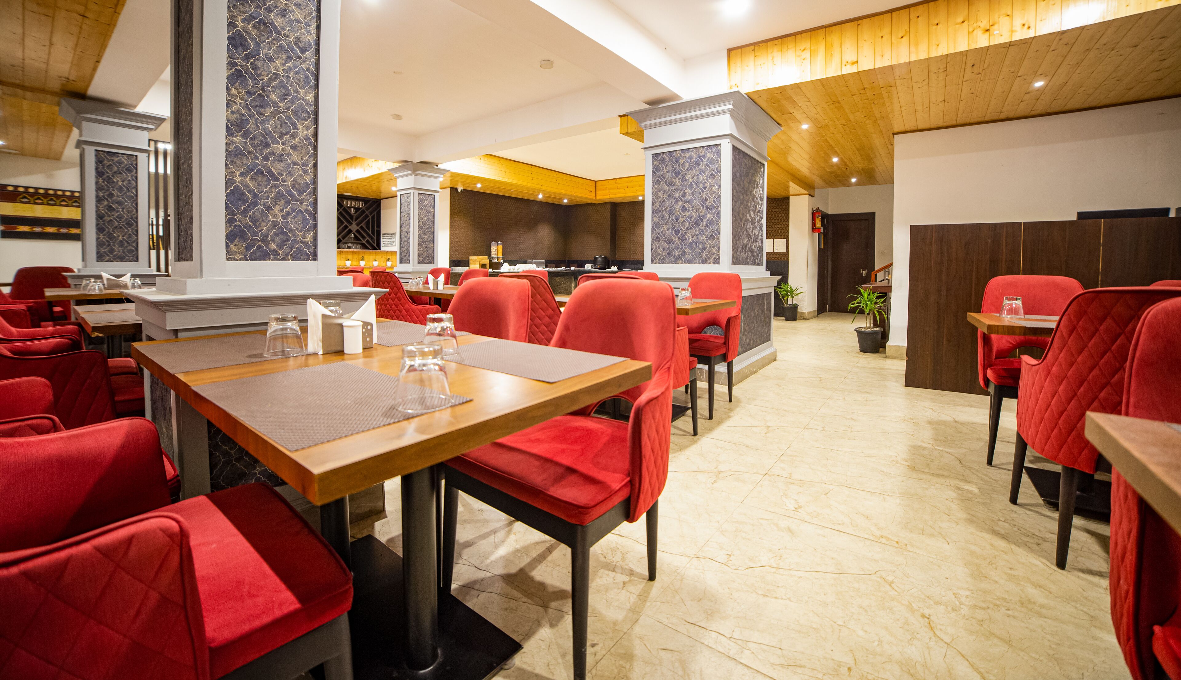 Un restaurant avec des chaises à revêtement rouge, une table en bois et un sol carrelé.