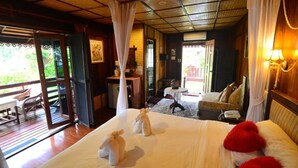 A room with a bed, a small table, a chair, and a view of the outdoors. - Viang Yonok Hotel Restaurant Sports Club (Chiang Saen)