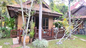 A wooden house with a porch, surrounded by tropical plants and a stone pathway. - Viang Yonok Hotel Restaurant Sports Club (Chiang Saen)