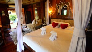 A hotel room with a large bed, two heart-shaped pillows, a bedside table, and a canopy bed. - Viang Yonok Hotel Restaurant Sports Club (Chiang Saen)