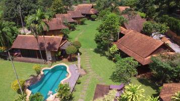 A residential area with multiple houses, a swimming pool, and lush greenery.