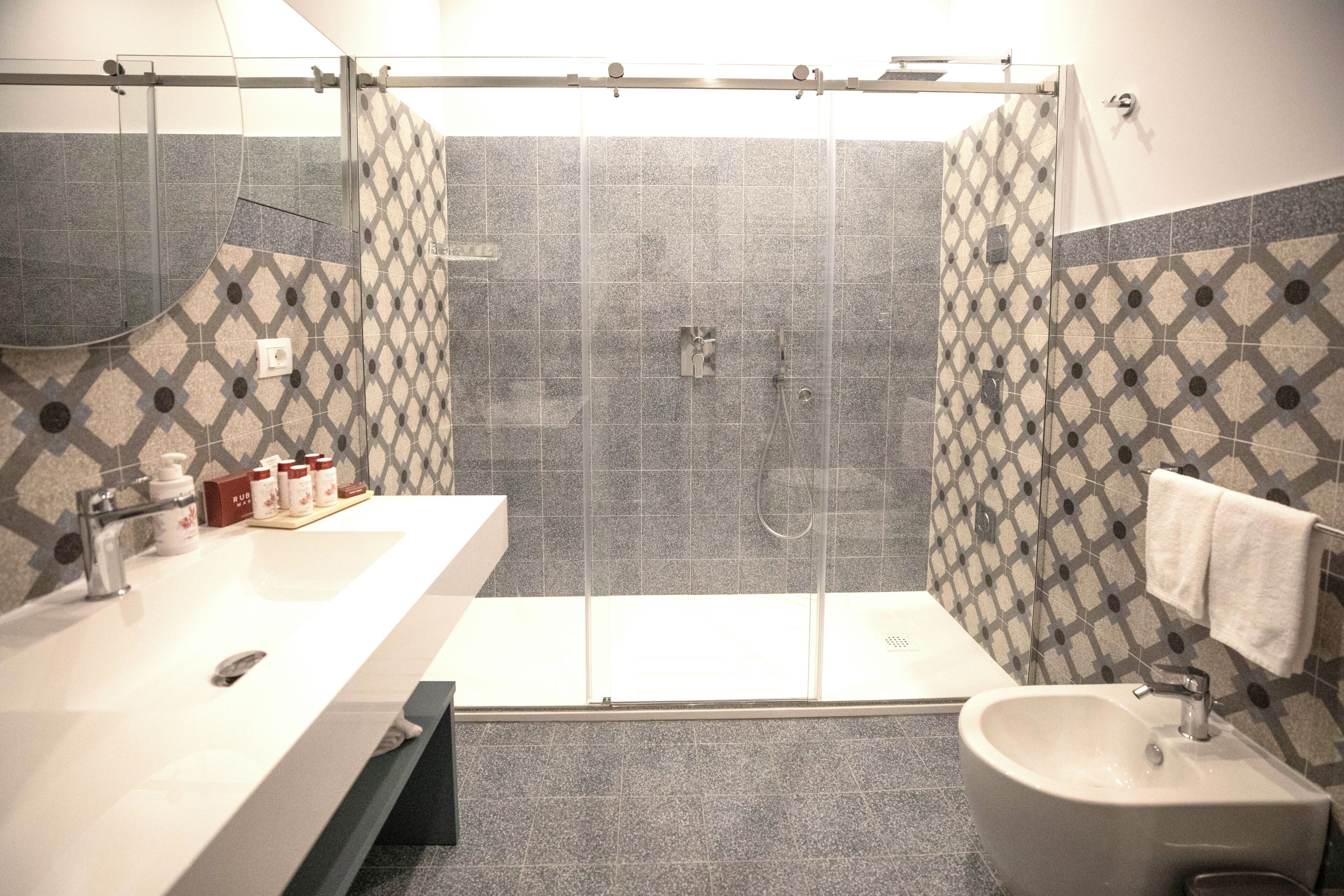 A bathroom with a large shower, a sink, and a bidet.